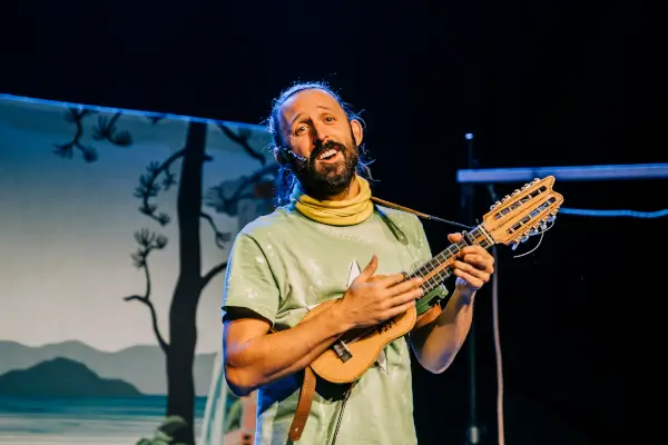 Ilustración alegre de Brais das Hortas tocando instrumentos en una huerta, rodeado de niños y verduras, en un ambiente festivo.