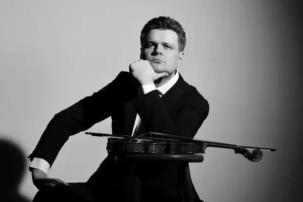 Imagen de una orquesta sinfónica en plena actuación, con el director Baldur Brönnimann al frente y un violinista solista.