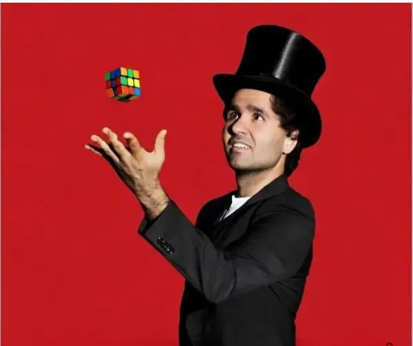 Mago realizando un truco en el escenario, con niños y adultos del público participando y riendo en el espectáculo 'Ser Diferente Mola'.