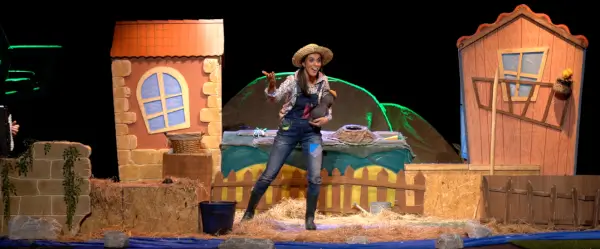 Imagen de un topito de marioneta con una expresión de sorpresa o indignación, con algo marrón sobre su cabeza, en un entorno de granja.