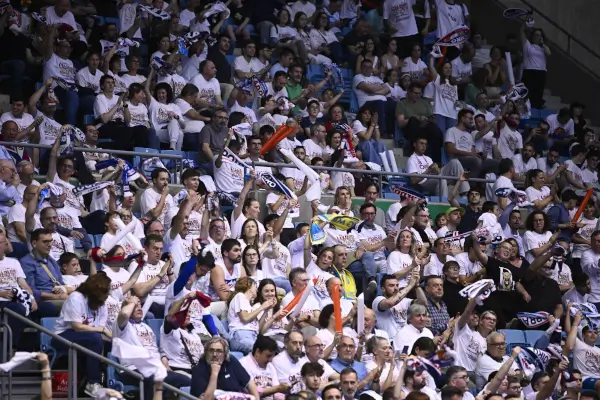 Jugadores de baloncesto en acción durante un partido de la Liga Endesa, con el balón en juego y la afición en las gradas.